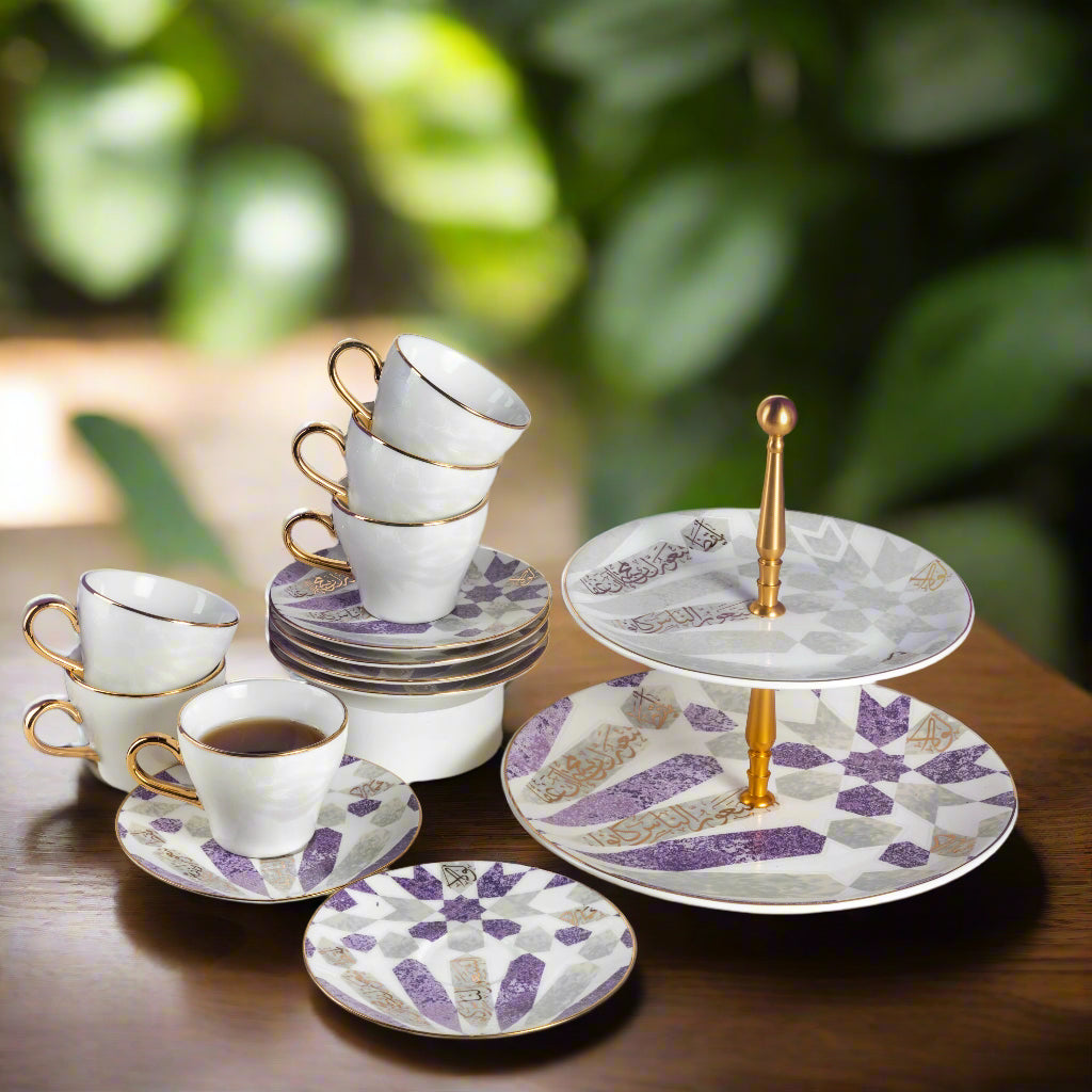 Ceramic tea set with cups, saucers, and a three-tiered stand on a wooden surface with a blurred green background.